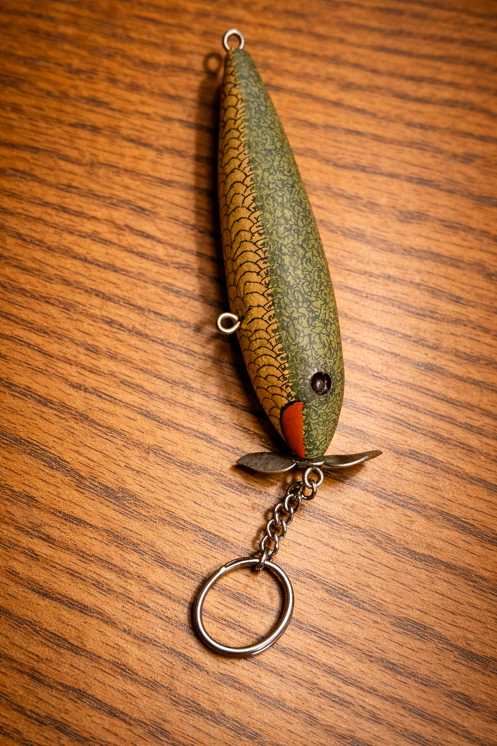 Vintage green and gold crankbait keychain on wood surface