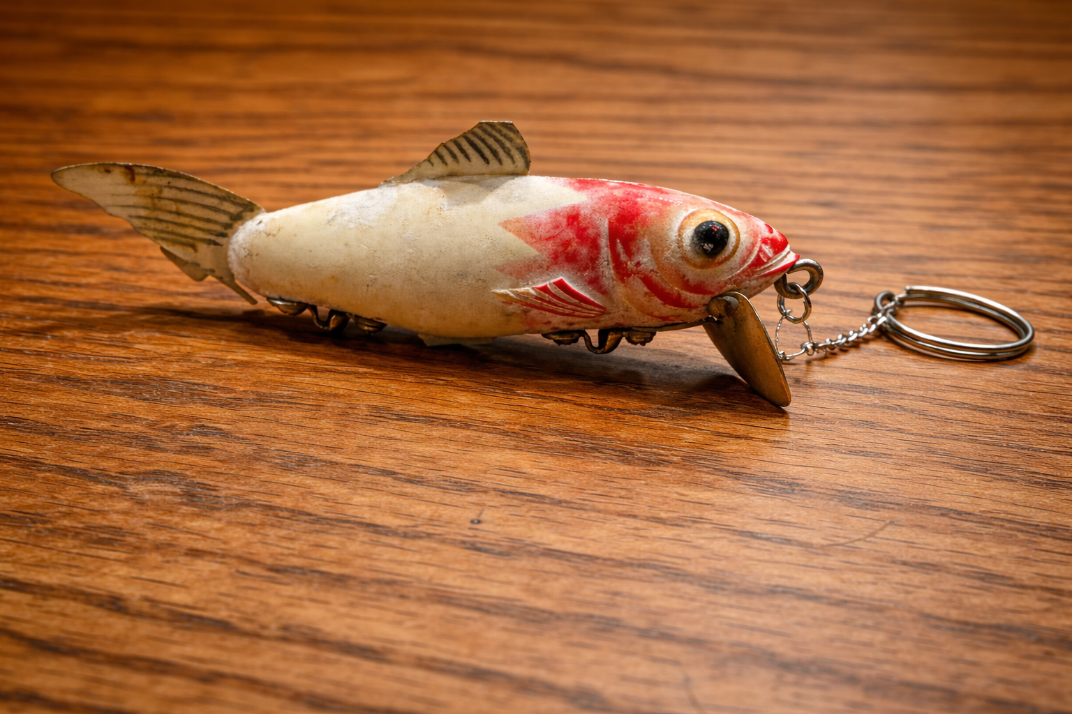 Vintage red and white crankbait keychain on wood surface